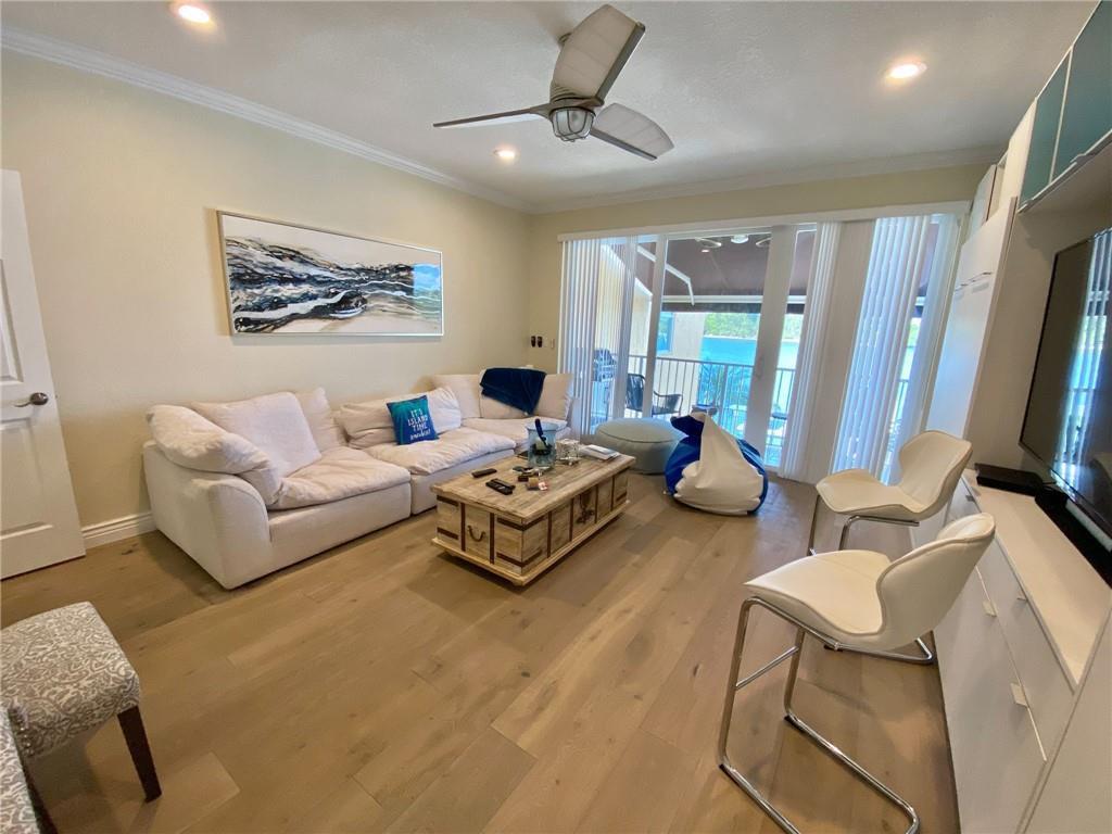 A living room features a white sectional sofa, wooden coffee table, and sliding glass doors — 4230 N Ocean Drive, Hollywood FL 33019, HOLLYWOOD, FL