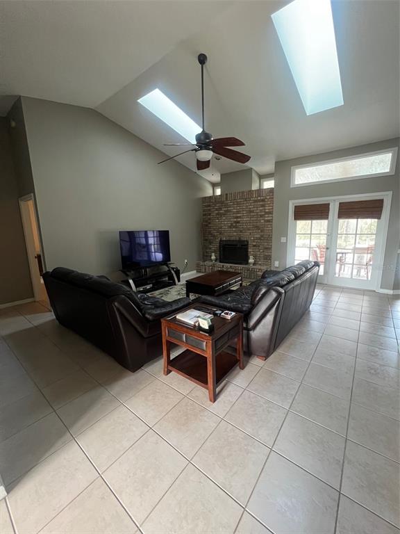 A living room features a vaulted ceiling with skylights, a brick fireplace, and tile flooring — 1545 ANTOINETTE COURT, OVIEDO, FL