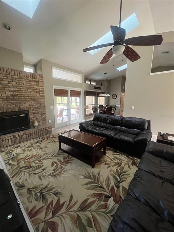 A living room features a brick fireplace, a large area rug, and a ceiling fan — 1545 ANTOINETTE COURT, OVIEDO, FL