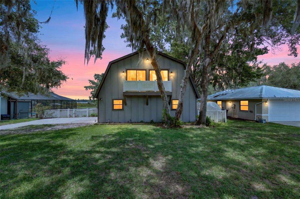 A two-story barn-style building with a balcony stands on a grassy lot at sunset — 11932 SE 196TH STREET, DUNNELLON, FL