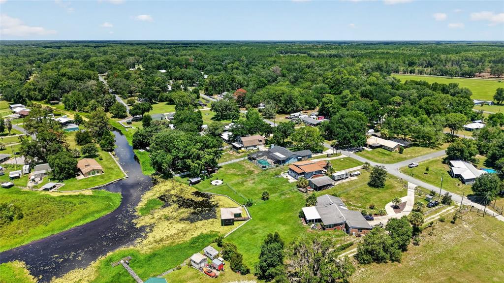 An aerial view shows houses scattered among trees and a winding waterway in a rural area — 11932 SE 196TH STREET, DUNNELLON, FL
