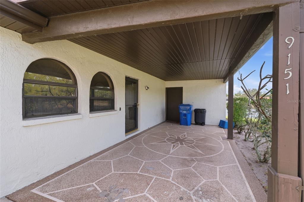 A covered patio features a decorative compass rose pattern on the concrete floor — 9151 LINGROVE ROAD, WEEKI WACHEE, FL