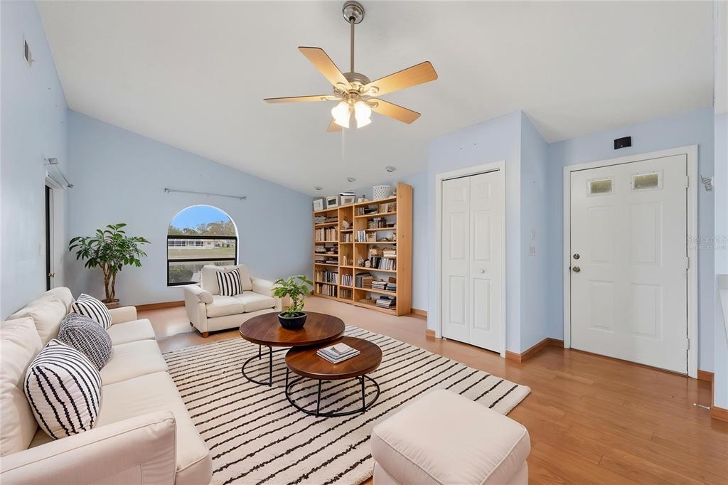 A living room with light blue walls, a ceiling fan, wood flooring, and a bookshelf — 9151 LINGROVE ROAD, WEEKI WACHEE, FL