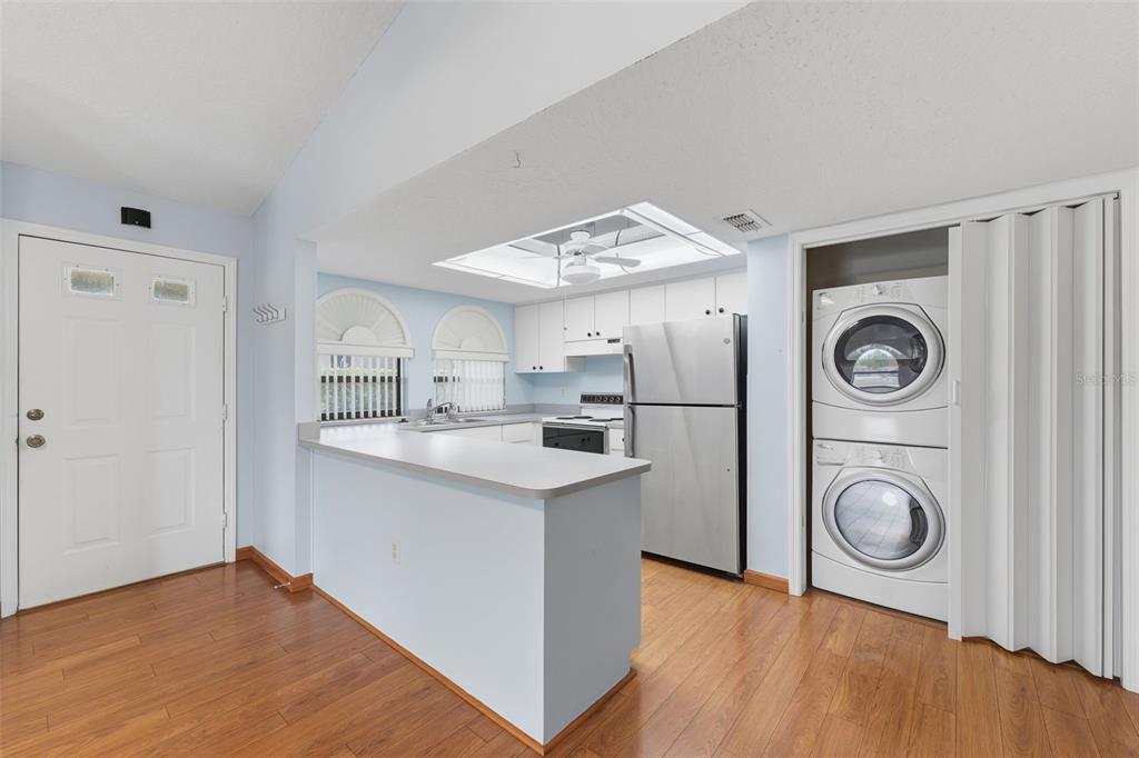A kitchen features a breakfast bar, stainless steel appliances, a skylight, and a stacked laundry unit — 9151 LINGROVE ROAD, WEEKI WACHEE, FL