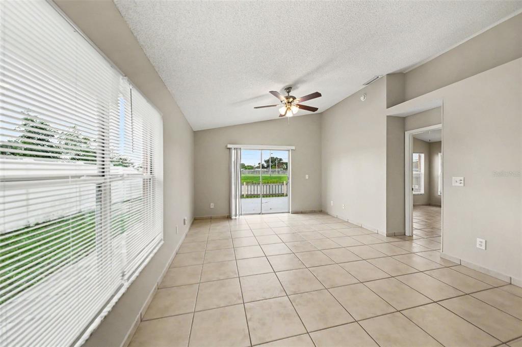 An empty living room with beige tile floors, a ceiling fan, and sliding glass doors — 1162 SHOSHANNA DRIVE, ORLANDO, FL