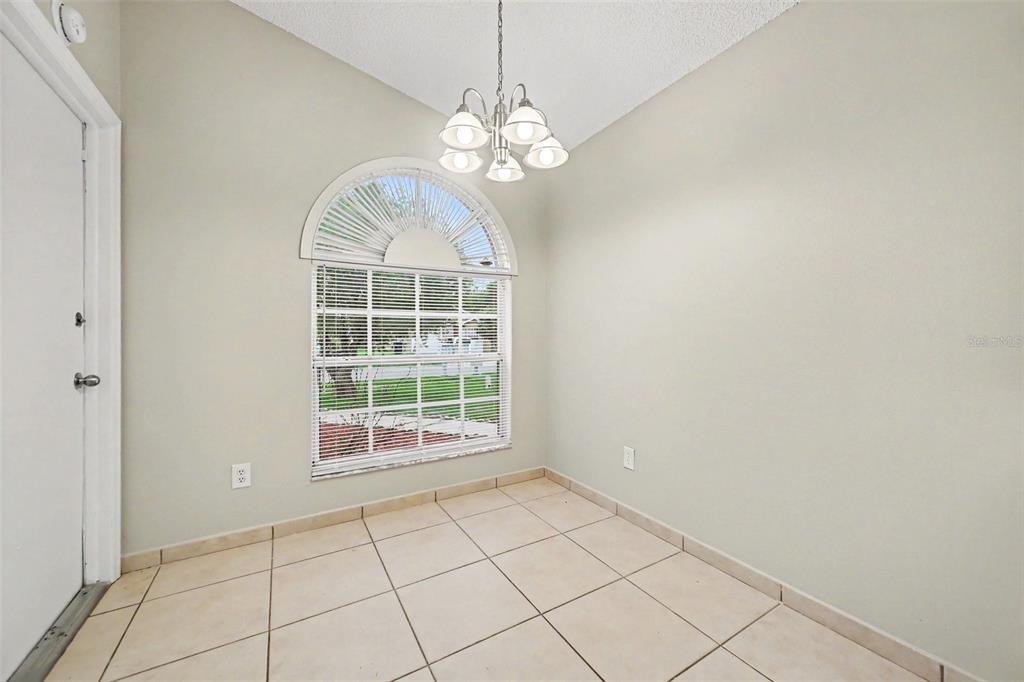 A dining area with tile flooring, a chandelier, and an arched window with blinds — 1162 SHOSHANNA DRIVE, ORLANDO, FL