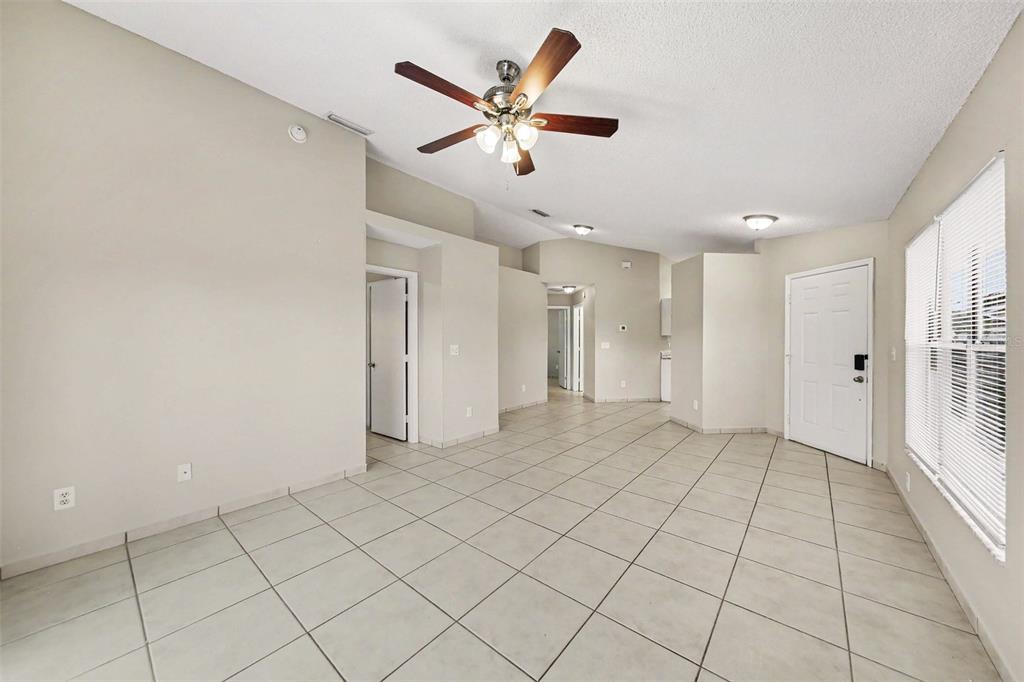 An interior view of a living room with light tile floors, beige walls, and a ceiling fan — 1162 SHOSHANNA DRIVE, ORLANDO, FL