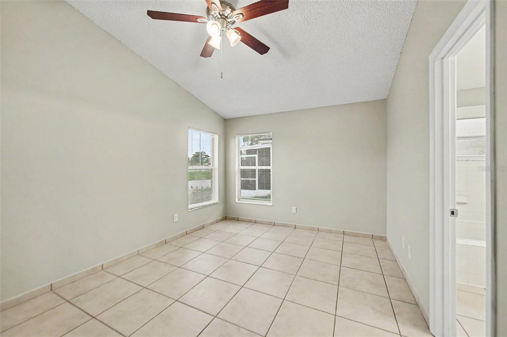 An empty bedroom with light-colored tile flooring, two windows, and a ceiling fan — 1162 SHOSHANNA DRIVE, ORLANDO, FL