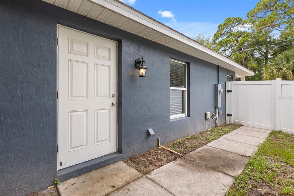 A gray exterior wall features a white door, a window, and a white privacy fence — 339 CHINABERRY AVENUE, OVIEDO, FL