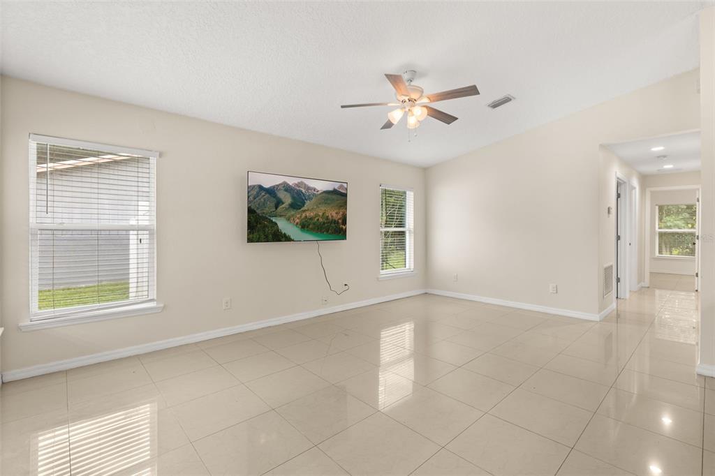 A bright living room features light tile floors, a ceiling fan, and a wall-mounted television — 339 CHINABERRY AVENUE, OVIEDO, FL