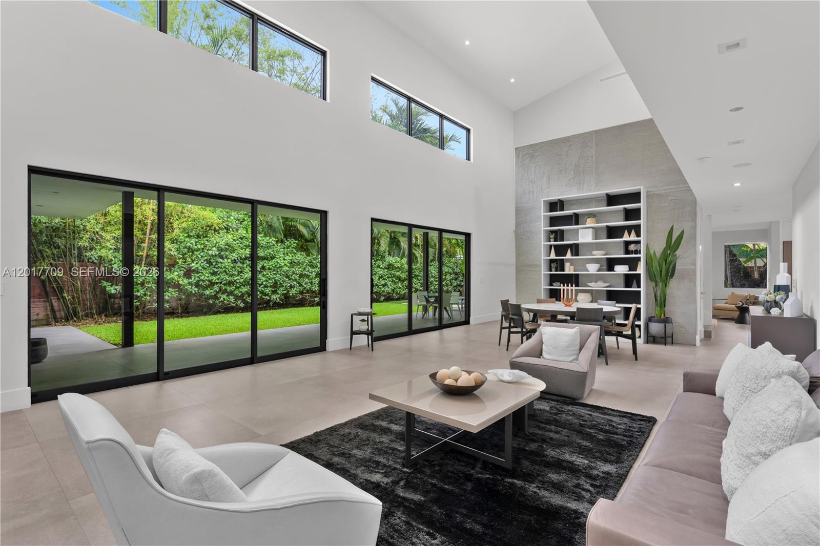 A spacious living and dining area features high ceilings, large windows, and sliding glass doors — 10 Samana Dr, Miami FL 33133, MIAMI, FL