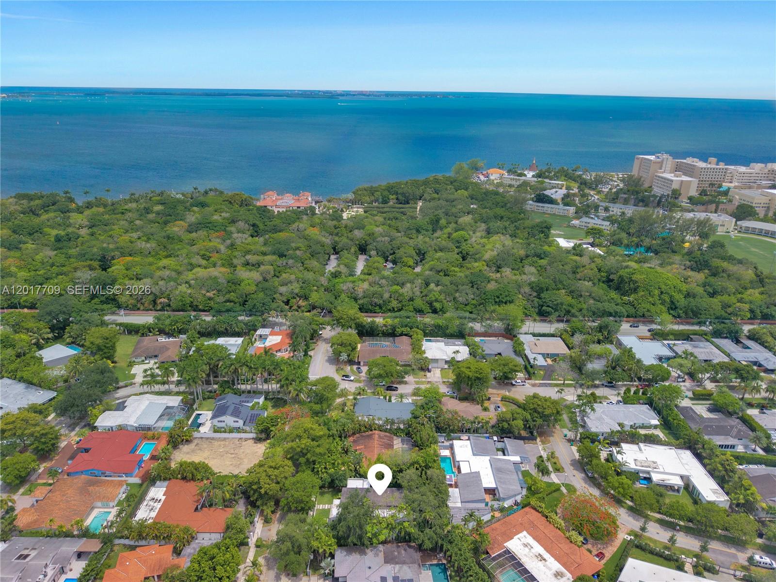An aerial view shows a residential neighborhood surrounded by dense trees near the ocean — 10 Samana Dr, Miami FL 33133, MIAMI, FL