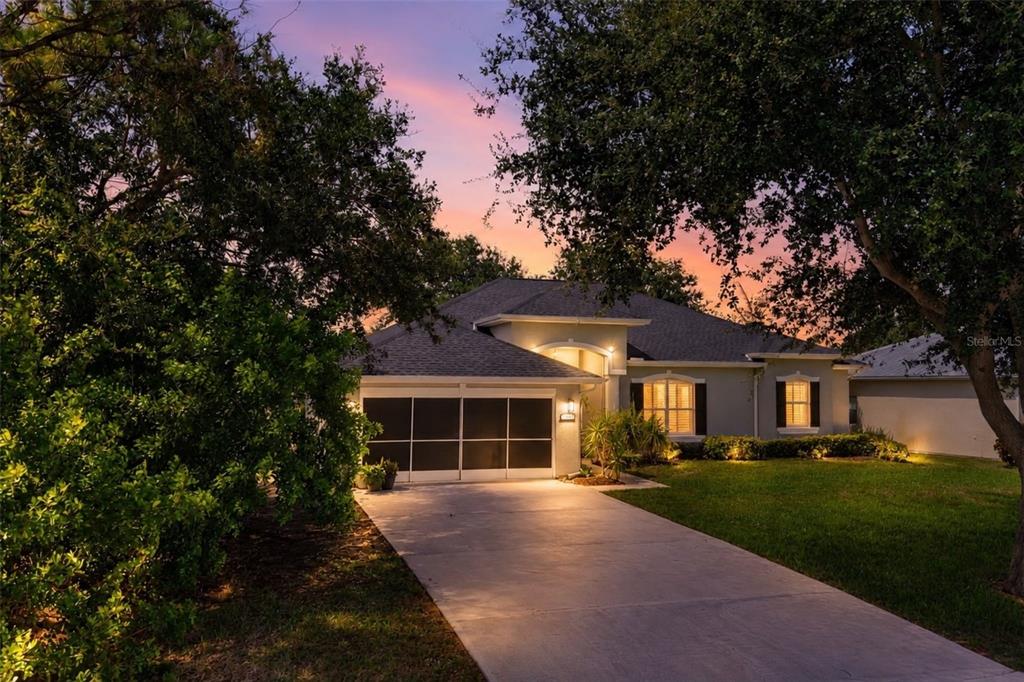 A single-story house with a screened garage door and a concrete driveway at sunset — 115 EMPIRE TERRACE, SEBASTIAN, FL