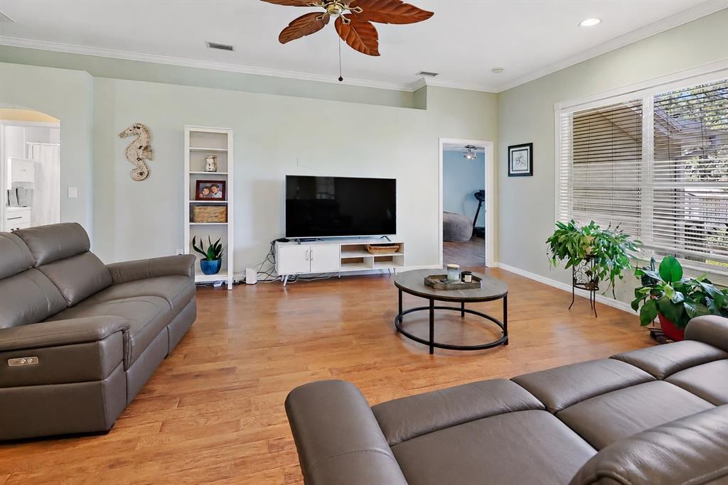 A living room features light green walls, hardwood floors, two leather sofas, and a television — 115 EMPIRE TERRACE, SEBASTIAN, FL