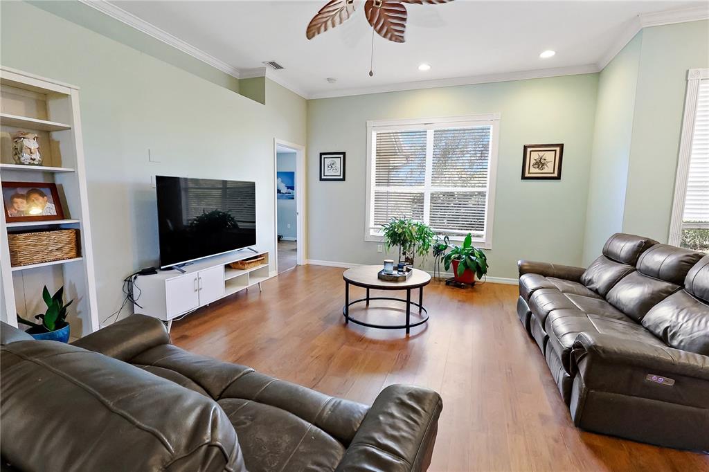 A living room features hardwood floors, a leather sofa, a television, and a ceiling fan — 115 EMPIRE TERRACE, SEBASTIAN, FL