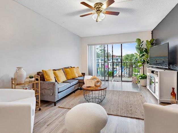 A living room features a gray sofa, a white armchair, and a sliding glass door — 1504 VIRGINIA AVENUE UNIT 203, DAYTONA BEACH, FL