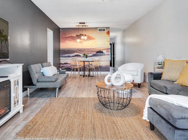 A living room features a gray sofa, a wire coffee table, and a beach mural wall — 1504 VIRGINIA AVENUE UNIT 203, DAYTONA BEACH, FL