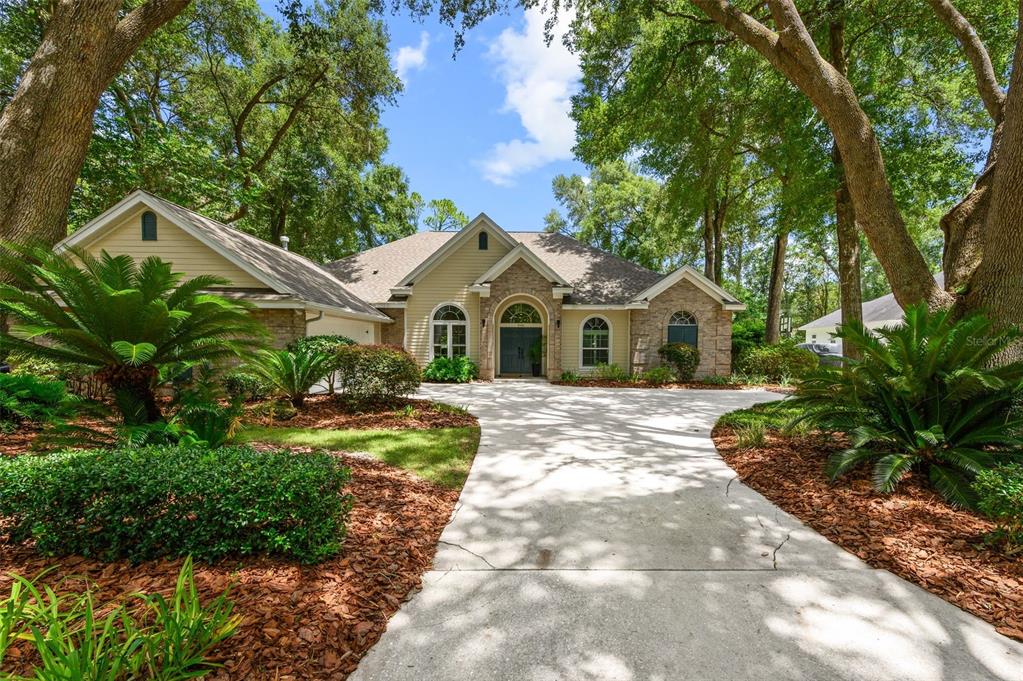A single-story house with a stone and siding facade sits behind a concrete driveway — 9340 SW 32ND PLACE, GAINESVILLE, FL