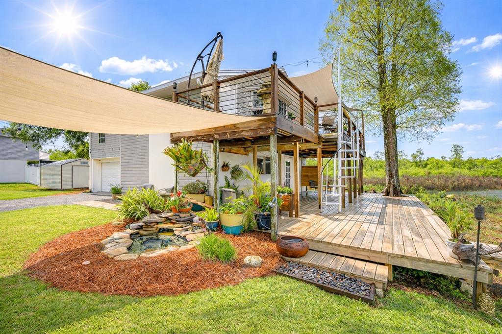 A two-story house features a large wooden deck, a spiral staircase, and a small pond — 1216 BRANDON LAKES AVENUE, VALRICO, FL