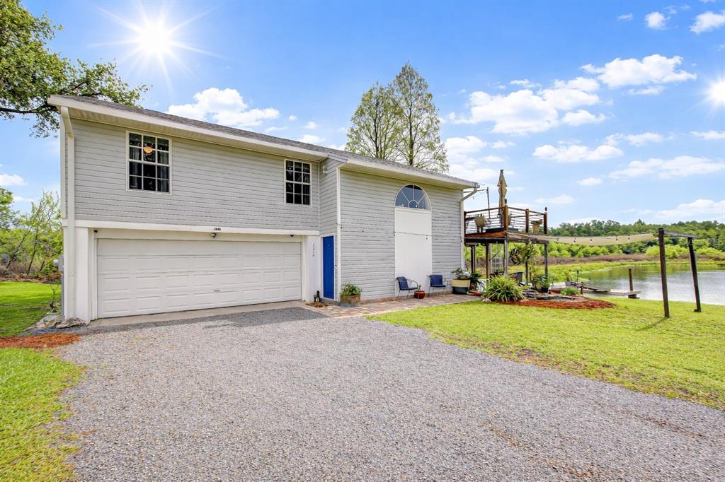 A two-story house with gray siding, a large garage, and a deck overlooking a lake — 1216 BRANDON LAKES AVENUE, VALRICO, FL