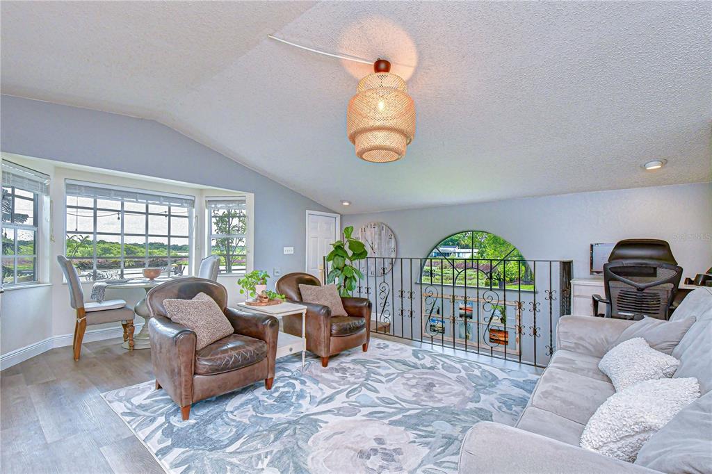 A living room with a vaulted ceiling, a woven pendant light, and a balcony railing — 1216 BRANDON LAKES AVENUE, VALRICO, FL