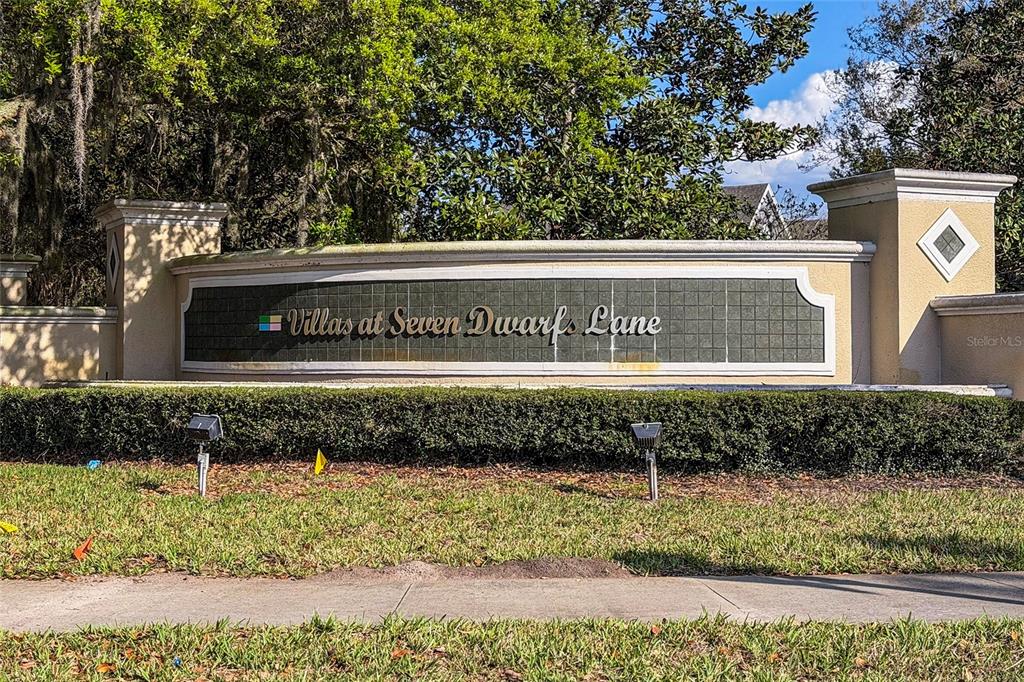 A beige stucco community entrance sign reads Villas at Seven Dwarfs Lane — 2611 GALA ROAD N UNIT 106, KISSIMMEE, FL
