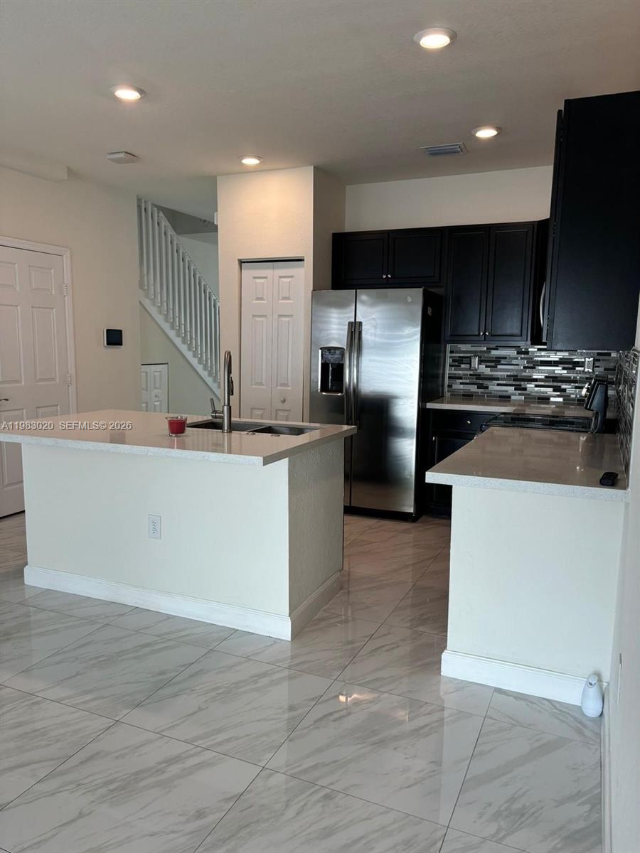 A kitchen features white countertops, dark cabinets, stainless steel appliances, and light-colored tile flooring — 3337 W 105th Ter, Hialeah FL 33018, HIALEAH, FL