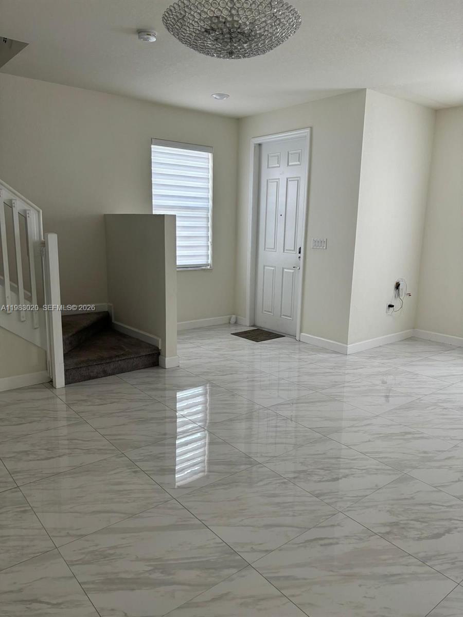 A bright entryway features white marble-look tile flooring, a staircase, and a front door — 3337 W 105th Ter, Hialeah FL 33018, HIALEAH, FL