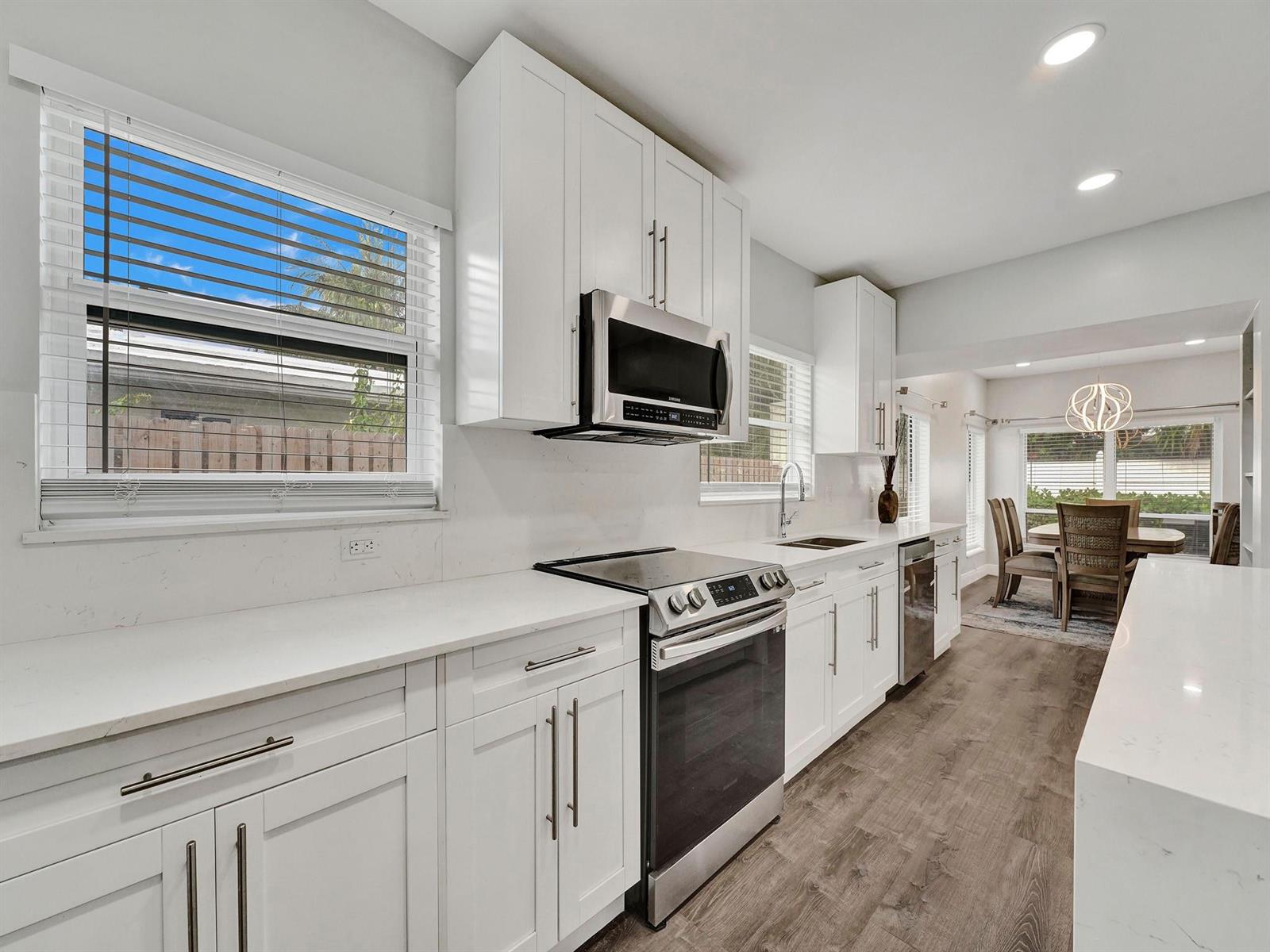 A modern kitchen features white cabinets, stainless steel appliances, and quartz countertops — 3261 Aqua Vista Drive, Pompano Beach FL 33062, POMPANO BEACH, FL