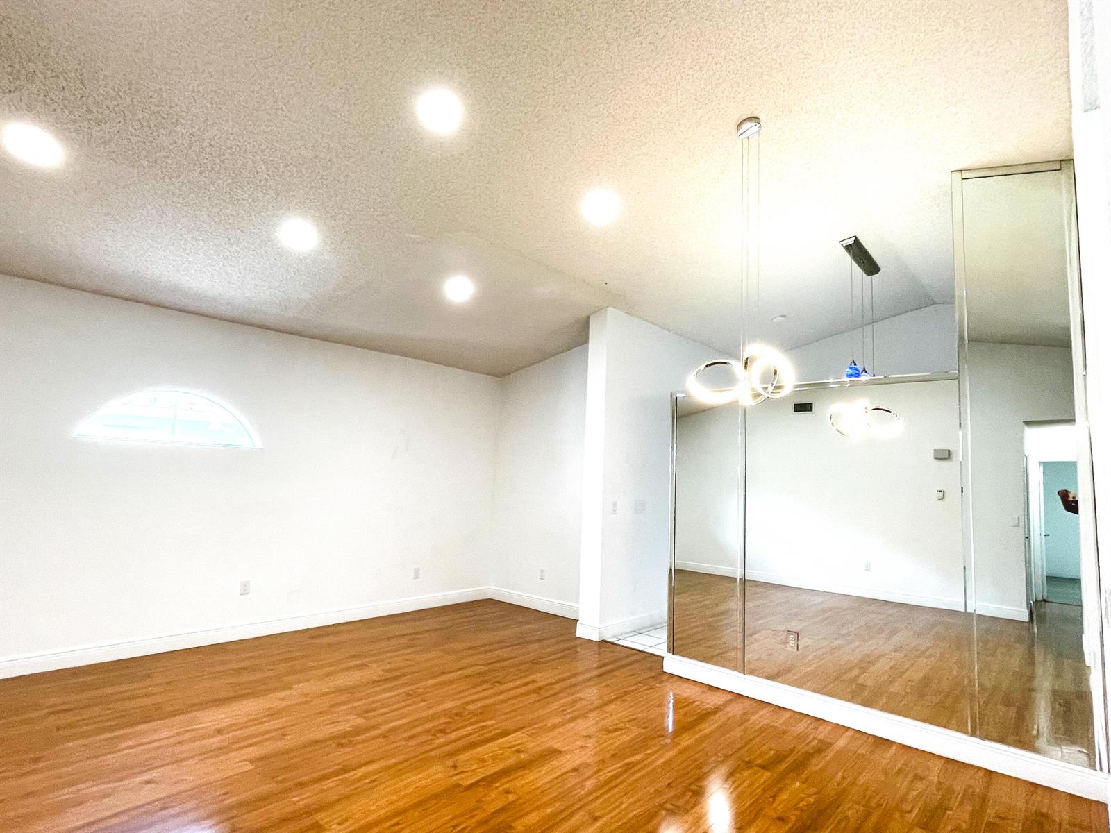 A bright room features wood-look flooring, recessed lighting, a modern chandelier, and mirrored wall panels — 5851 Bristol Lane, Davie FL 33331, DAVIE, FL