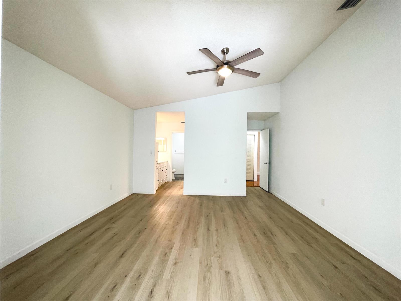 An empty bedroom with light wood-look flooring, white walls, a ceiling fan, and two doorways — 5851 Bristol Lane, Davie FL 33331, DAVIE, FL
