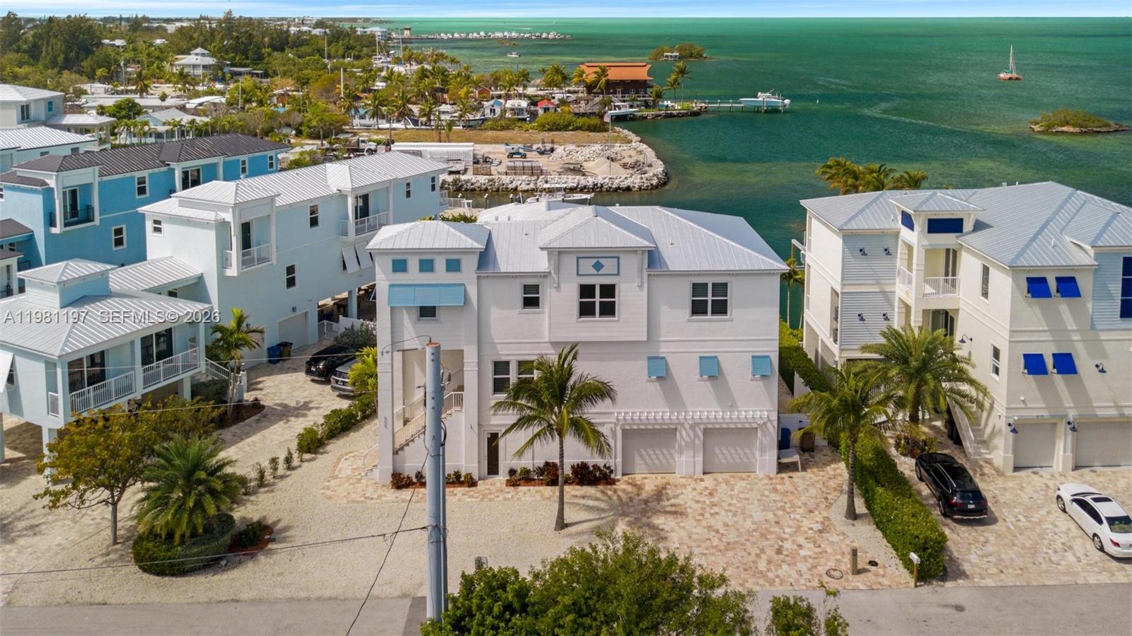 A three-story white house with a metal roof stands near a coastal waterfront — 865 50th Street Gulf, Marathon FL 33050, MARATHON, FL
