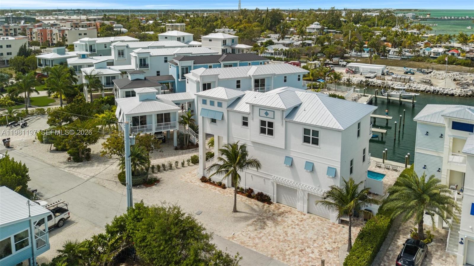 An aerial view shows a white multi-story house with a metal roof and paved driveway — 865 50th Street Gulf, Marathon FL 33050, MARATHON, FL