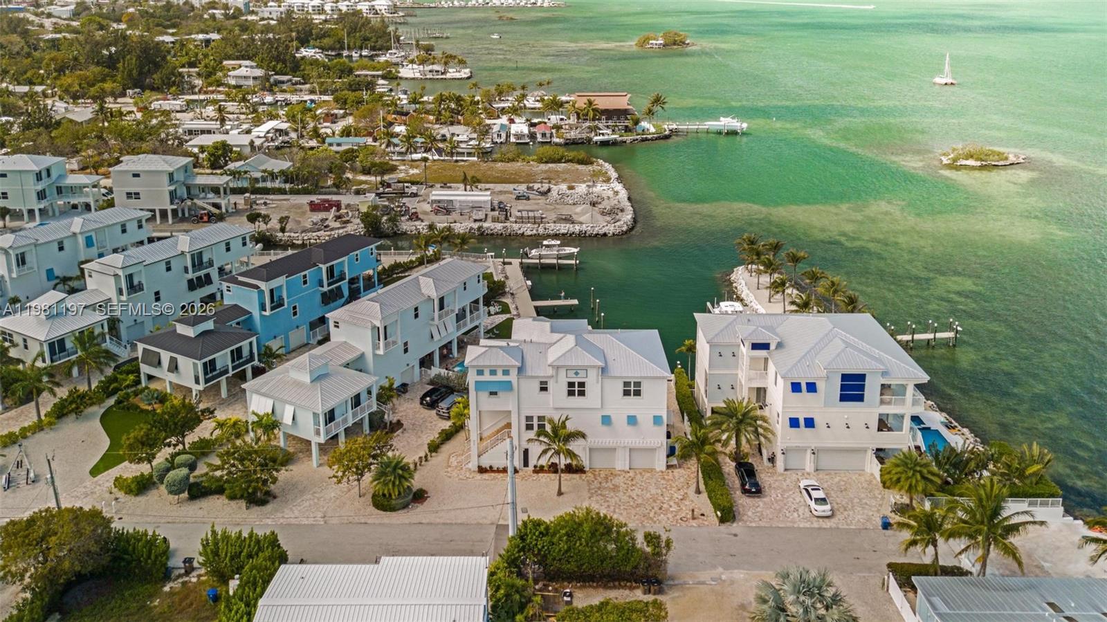 An aerial view shows several multi-story coastal homes situated along a canal and bay — 865 50th Street Gulf, Marathon FL 33050, MARATHON, FL