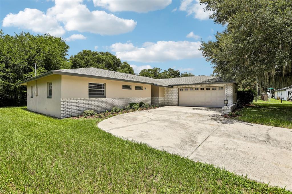 A single-story house with a beige stucco and white brick exterior and a two-car garage — 28 LINDA LANE, KISSIMMEE, FL