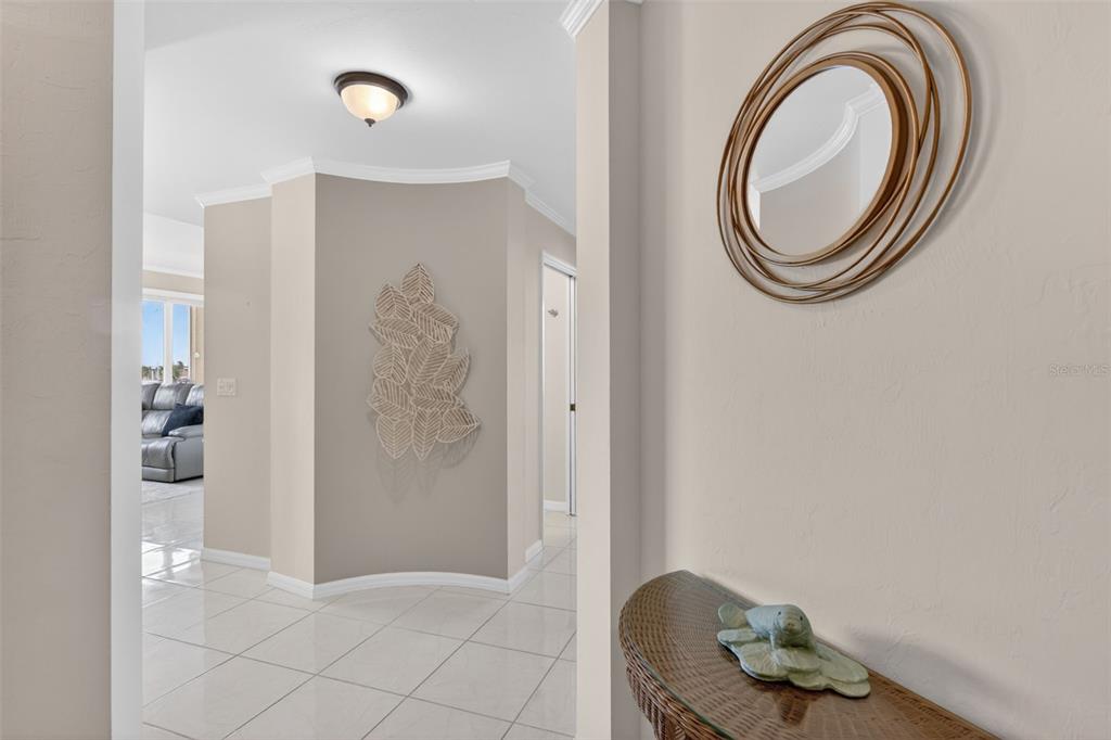 A hallway features tiled floors, a curved wall with leaf decor, and a decorative mirror — 2060 MATECUMBE KEY ROAD UNIT 2506, PUNTA GORDA, FL