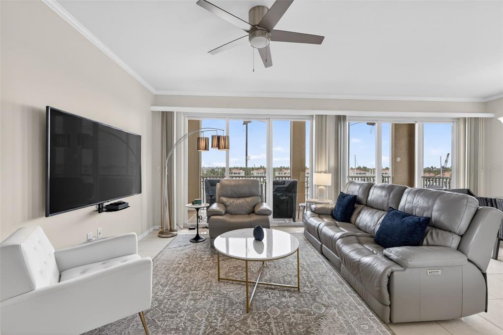 A living room features a grey leather sofa, a white armchair, and a sliding glass door — 2060 MATECUMBE KEY ROAD UNIT 2506, PUNTA GORDA, FL