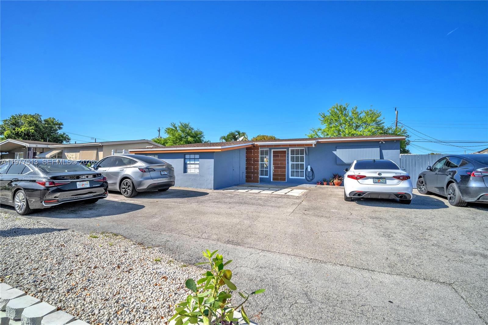 A single-story house with a blue exterior and a paved driveway featuring four parked cars — 7151 Taft St, Hollywood FL 33024, HOLLYWOOD, FL