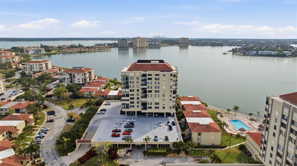 An aerial view shows a multi-story apartment building with a parking lot and waterfront — 6322 PALMA DEL MAR BOULEVARD S UNIT 606, ST PETERSBURG, FL