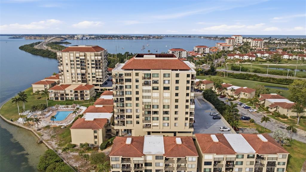 An aerial view shows a multi-story residential complex with a pool near the water — 6322 PALMA DEL MAR BOULEVARD S UNIT 606, ST PETERSBURG, FL