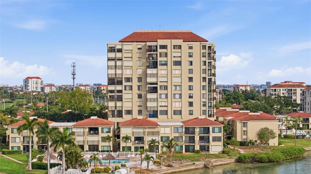 An aerial view shows a multi-story apartment complex with a pool near the water — 6322 PALMA DEL MAR BOULEVARD S UNIT 606, ST PETERSBURG, FL