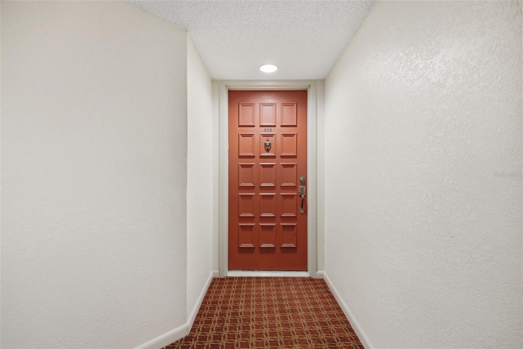 A red door with a knocker and the number 606 sits at the end of a hallway — 6322 PALMA DEL MAR BOULEVARD S UNIT 606, ST PETERSBURG, FL