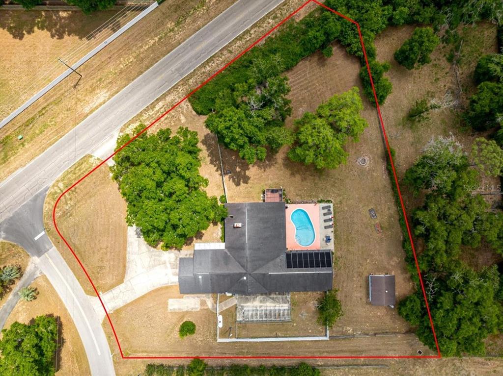 An aerial view shows a house with a pool and solar panels on a large lot — 11470 SE 73RD COURT, BELLEVIEW, FL