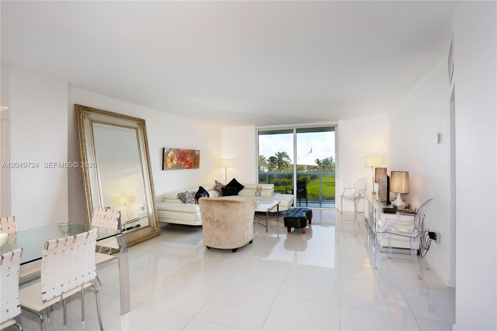 A bright living and dining area features white tile floors, a large mirror, and balcony access — 10275 Collins Ave # 335, Bal Harbour FL 33154, BAL HARBOUR, FL