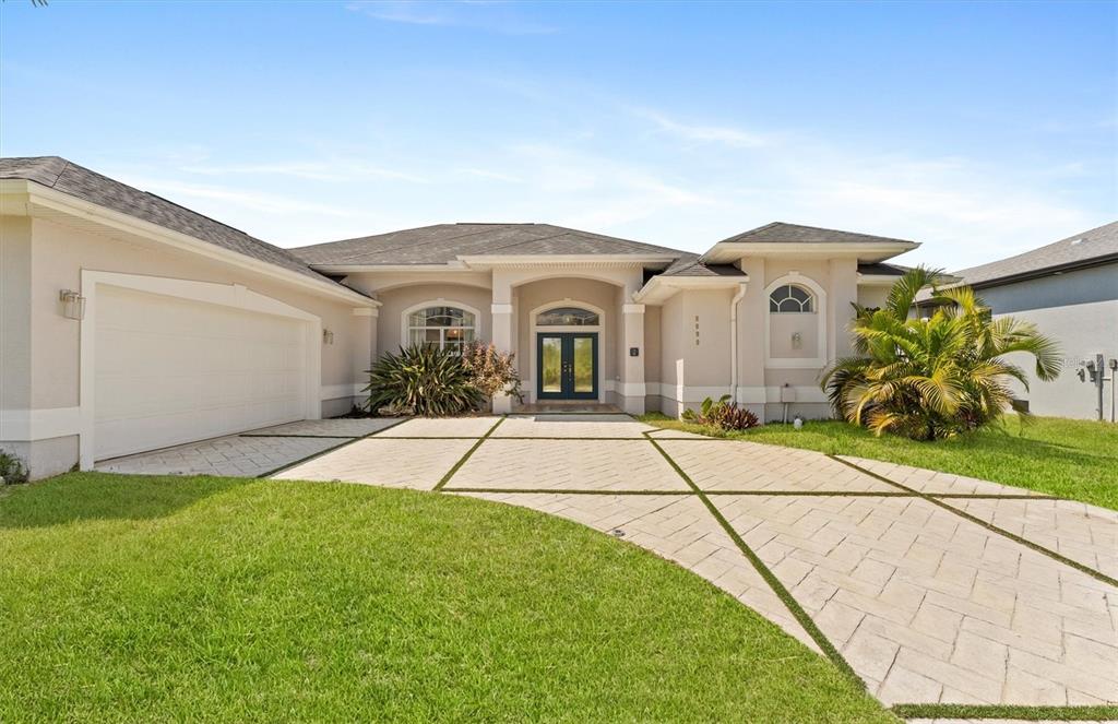 A single-story house with a beige stucco exterior, a multi-car garage, and a paved driveway — 8090 ARLEWOOD CIRCLE, PORT CHARLOTTE, FL