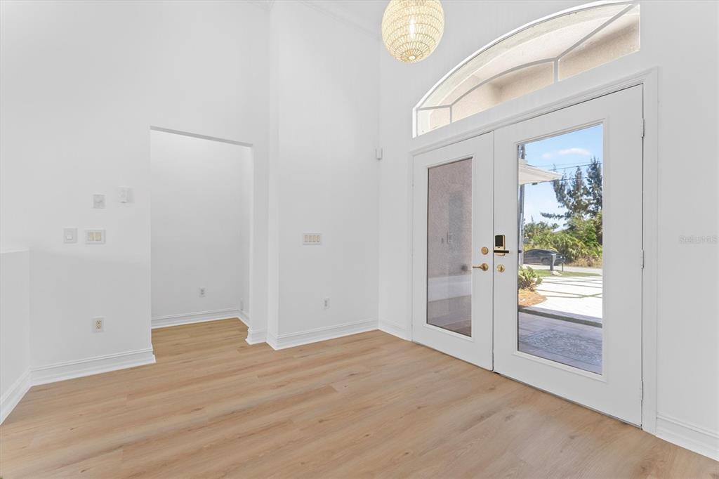 An entryway features light wood flooring, white walls, a high ceiling, and double glass doors — 8090 ARLEWOOD CIRCLE, PORT CHARLOTTE, FL