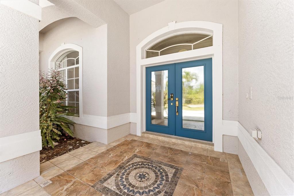 A covered entryway features a blue double door, a tiled floor, and a decorative medallion — 8090 ARLEWOOD CIRCLE, PORT CHARLOTTE, FL