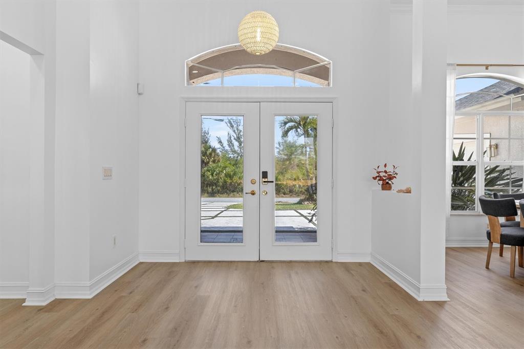 A bright foyer features white walls, light wood-look flooring, and double glass entry doors — 8090 ARLEWOOD CIRCLE, PORT CHARLOTTE, FL