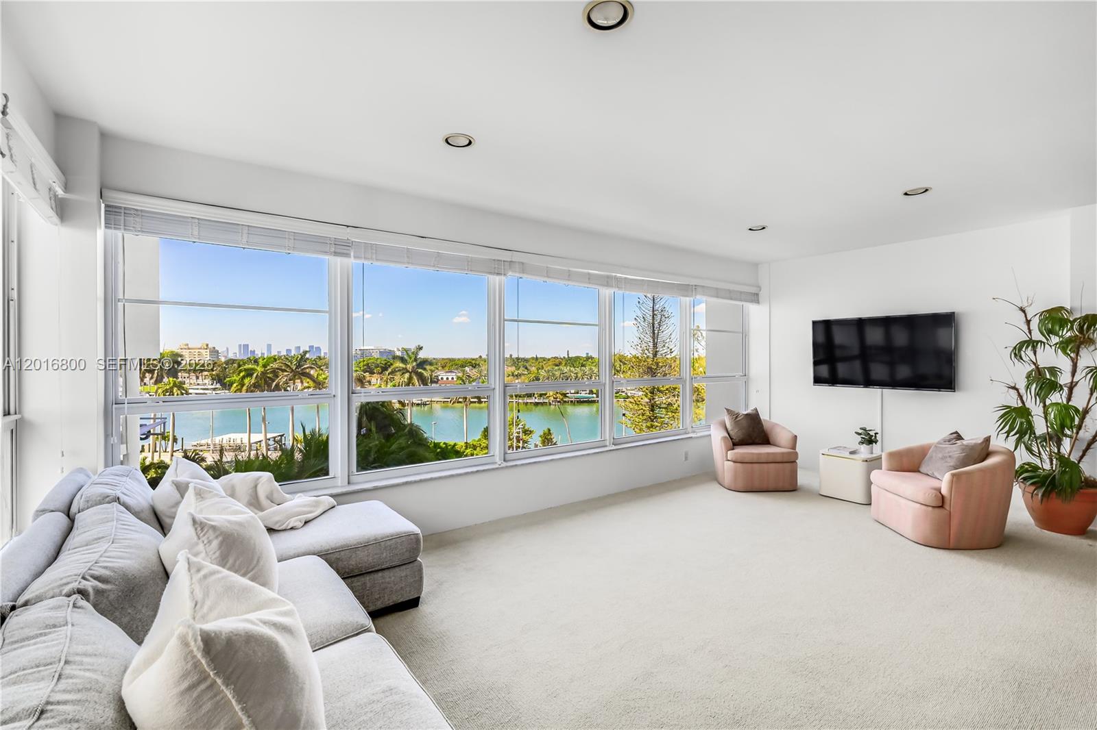 A living room features a large sectional sofa, two pink armchairs, and floor-to-ceiling windows — 4925 Collins Ave # 5F, Miami Beach FL 33140, MIAMI BEACH, FL