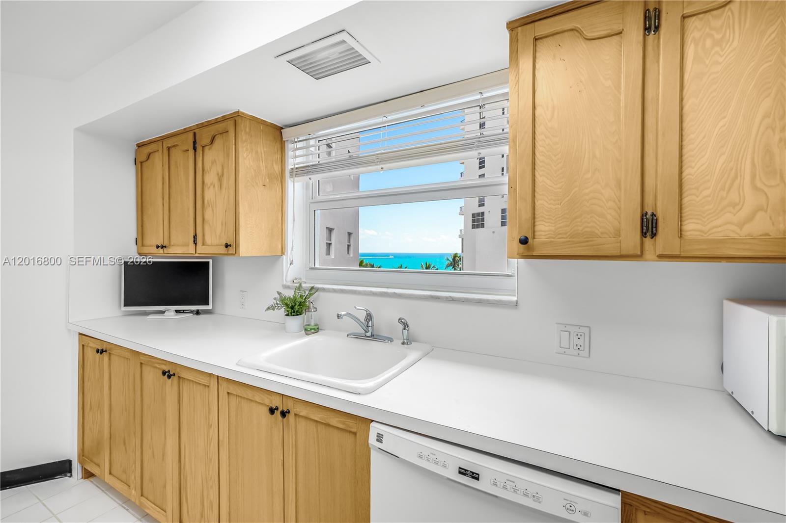 A kitchen features light wood cabinets, white countertops, a white sink, and an ocean view — 4925 Collins Ave # 5F, Miami Beach FL 33140, MIAMI BEACH, FL